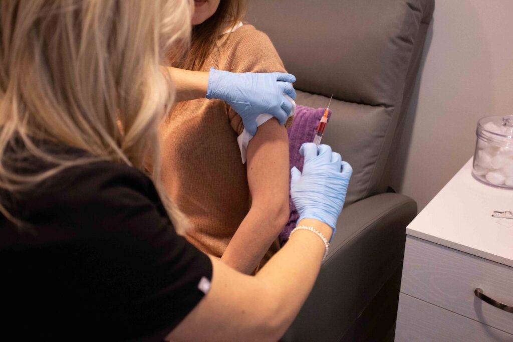 Healthcare professional giving a vitamin booster shot to a patient in a wellness clinic